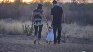 mom and dad walking with a child outside at twilight