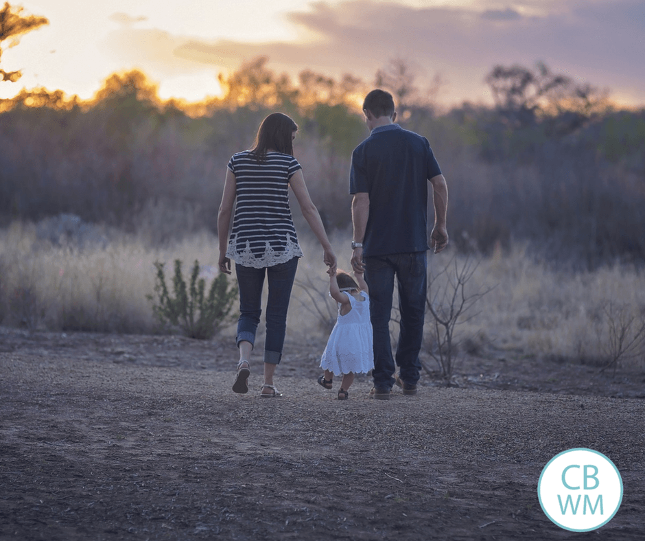 mom and dad walking with a child outside at twilight