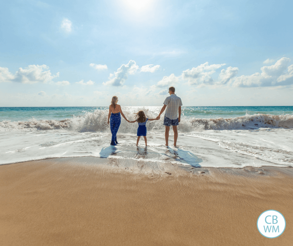 family standing in ocean waves at beach