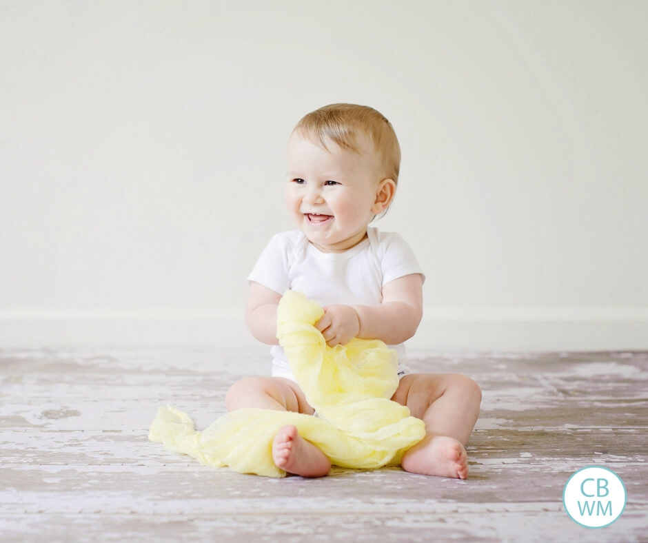 Cute Pretoddler smiling as he/she plays with yellow fabric