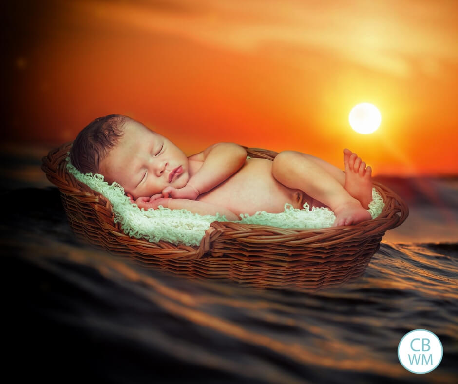 Sleeping baby in a basket on the water at sunset