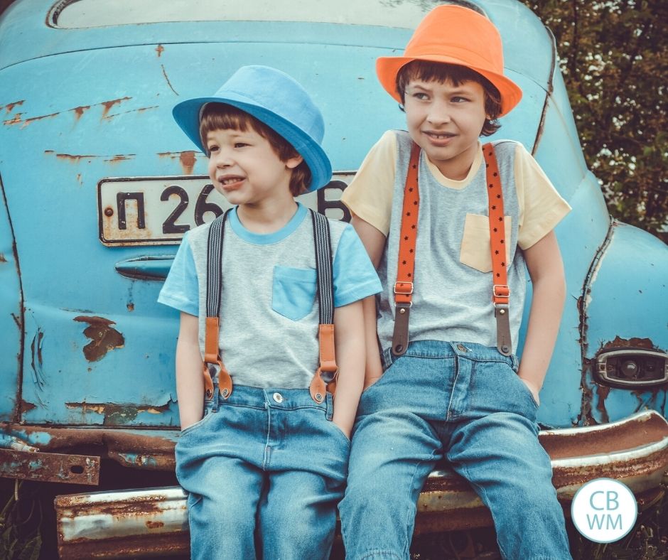 Siblings sitting on the bumper of a car