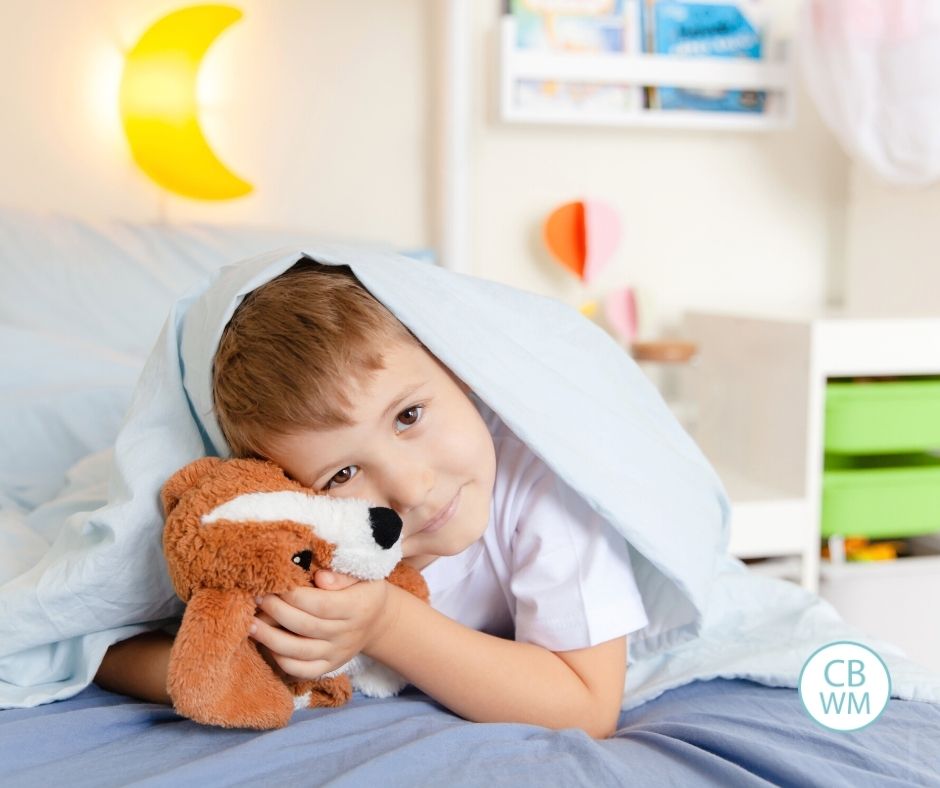 toddler holding stuffed animal in bed