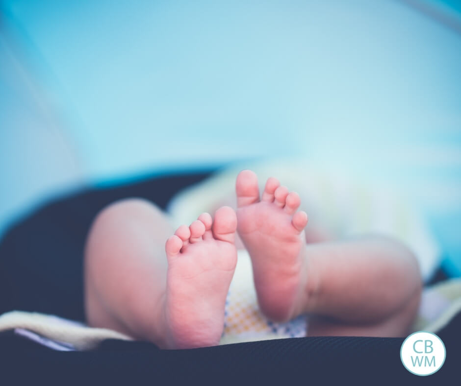 Baby lying on a bed. All you see is feet and legs