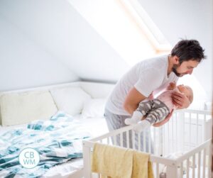 Father putting baby to bed in her crib