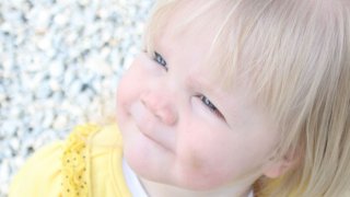 2 year old dressed in yellow and black sitting on the ground looking up