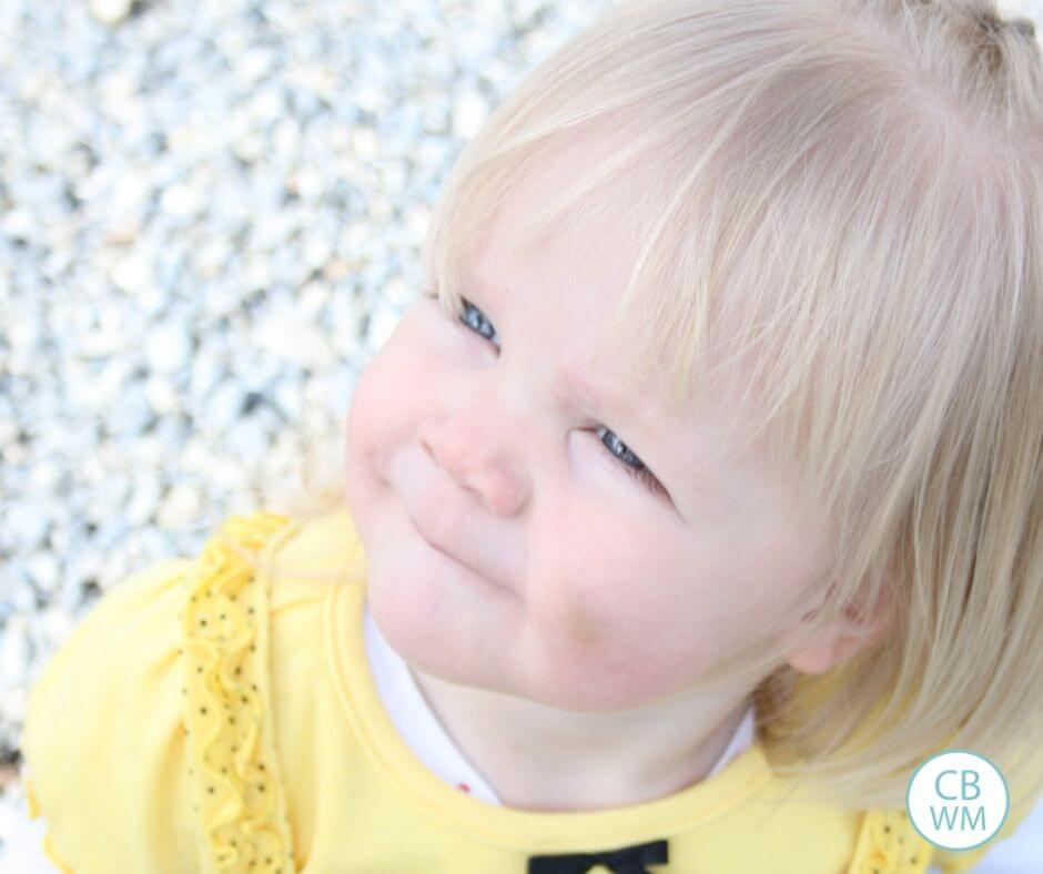 2 year old dressed in yellow and black sitting on the ground looking up