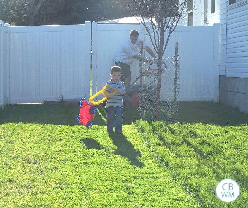 Young boy carrying his toy lawn mower