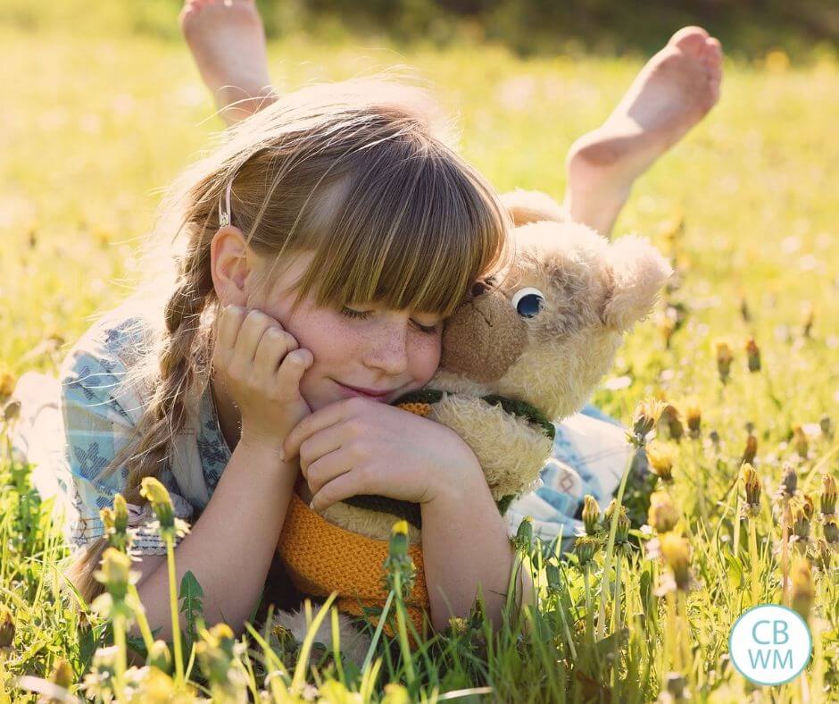 Girl hugging a stuffed animal on the grass