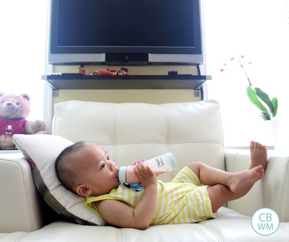 Baby drinking milk from a bottle on the couch