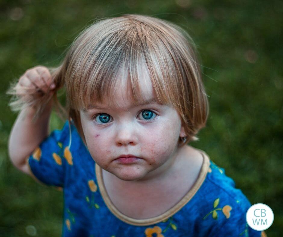 Little toddler with blue eyes standing on grass