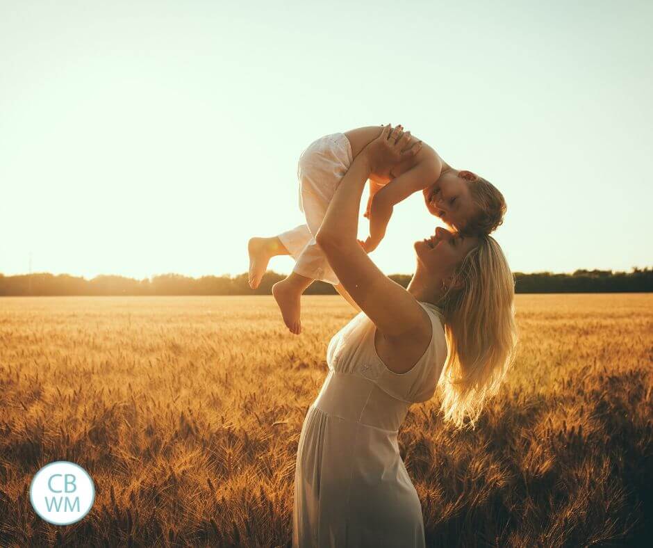 Mom lifting todder above her head out in a field