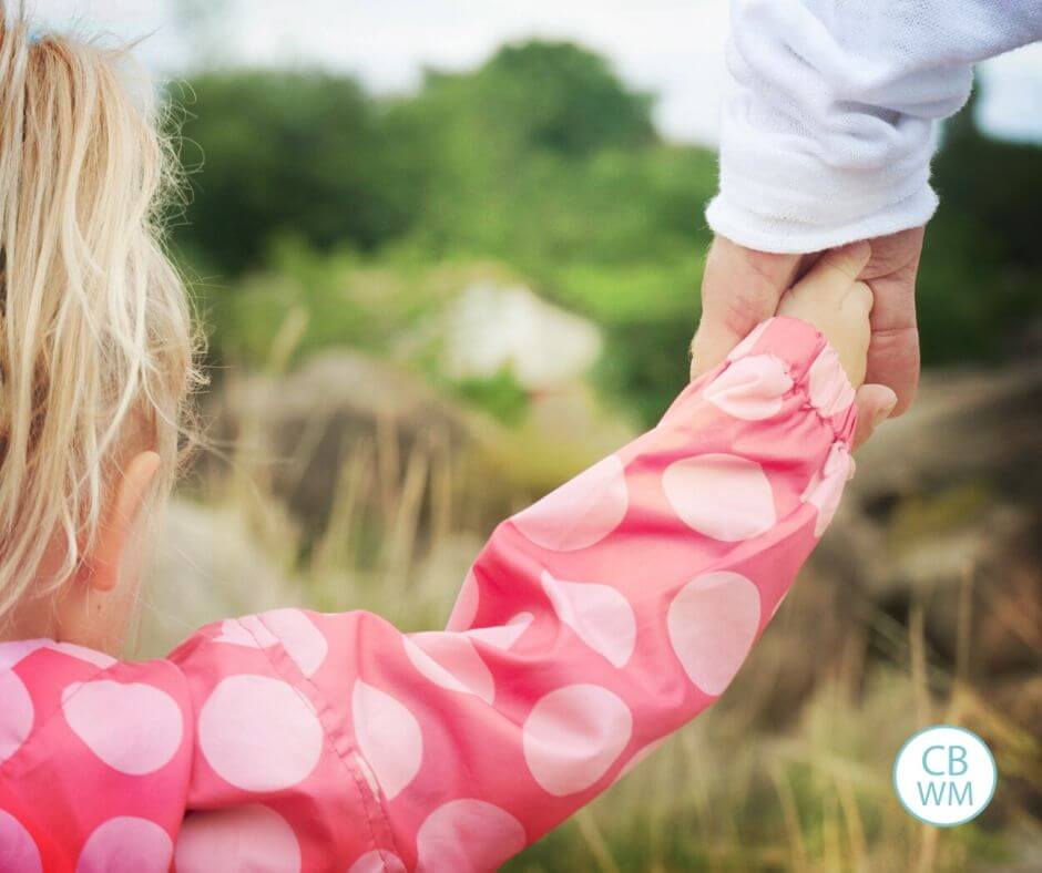 parent and child holding hands as they walk outside