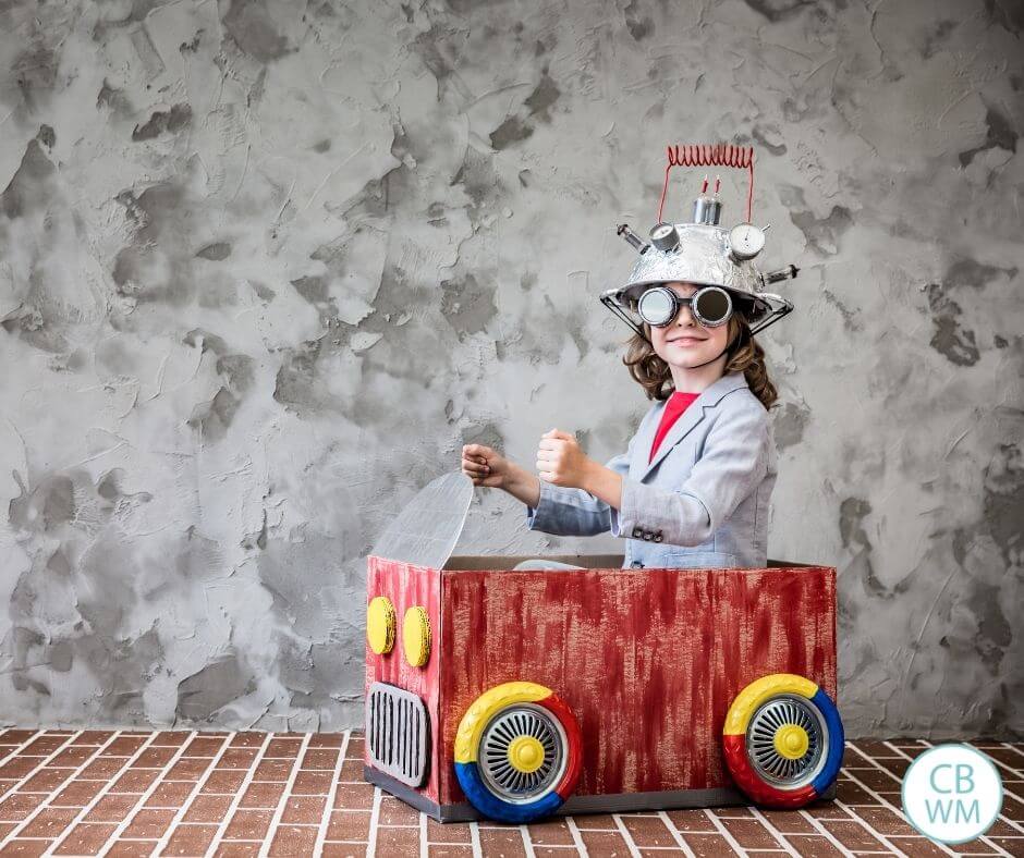 Child playing in cardboard car