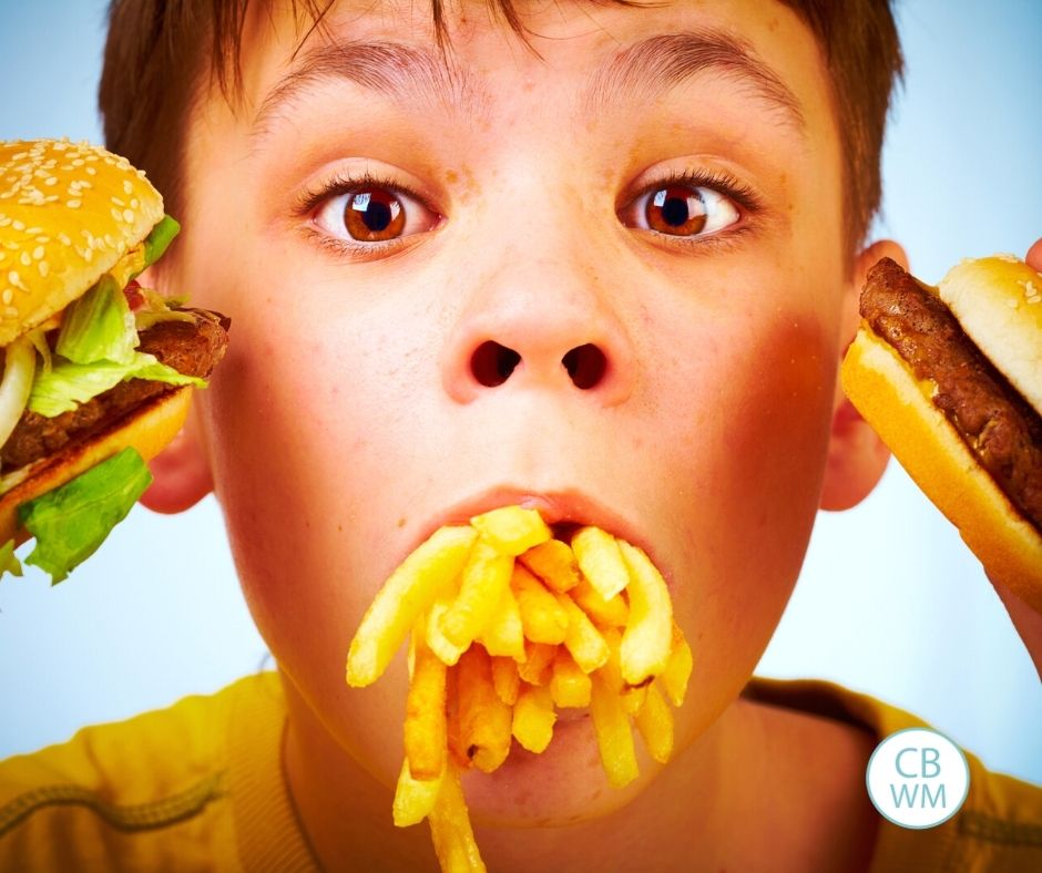 Child eating a lot of food and holding food up to face