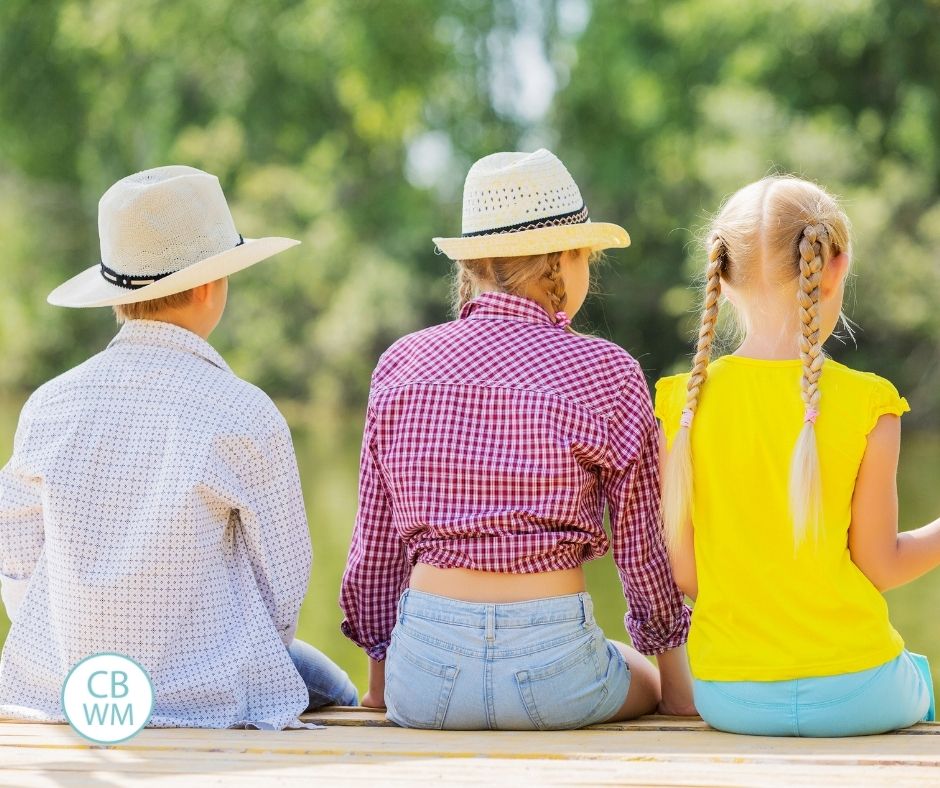 three children sitting on a dock