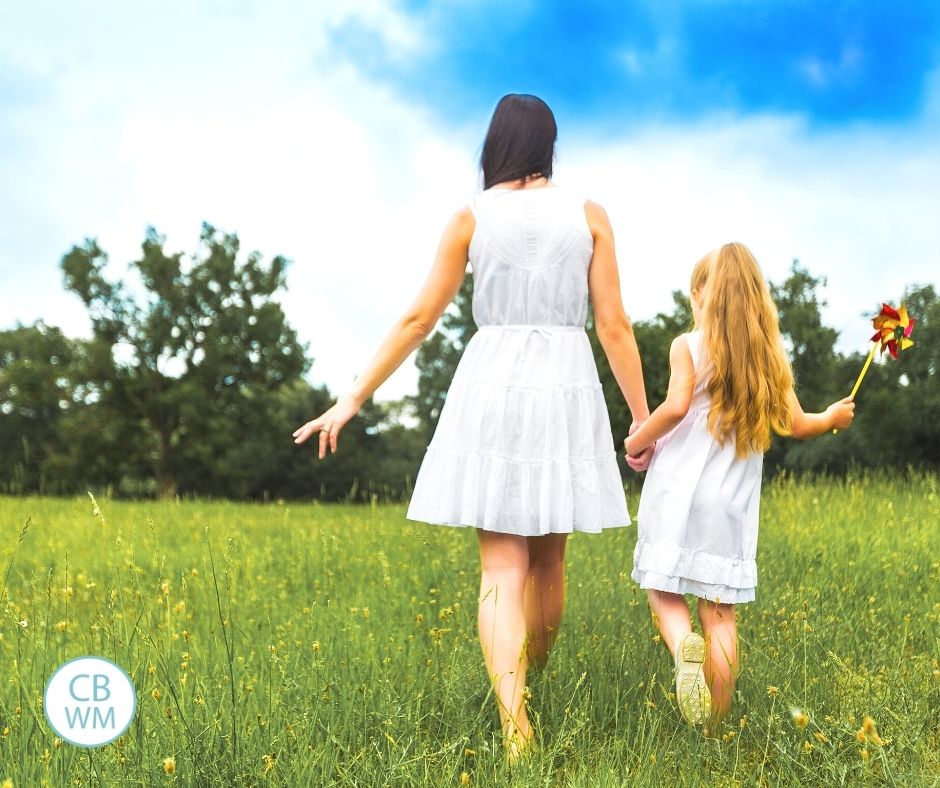 Mom and daughter walking through field