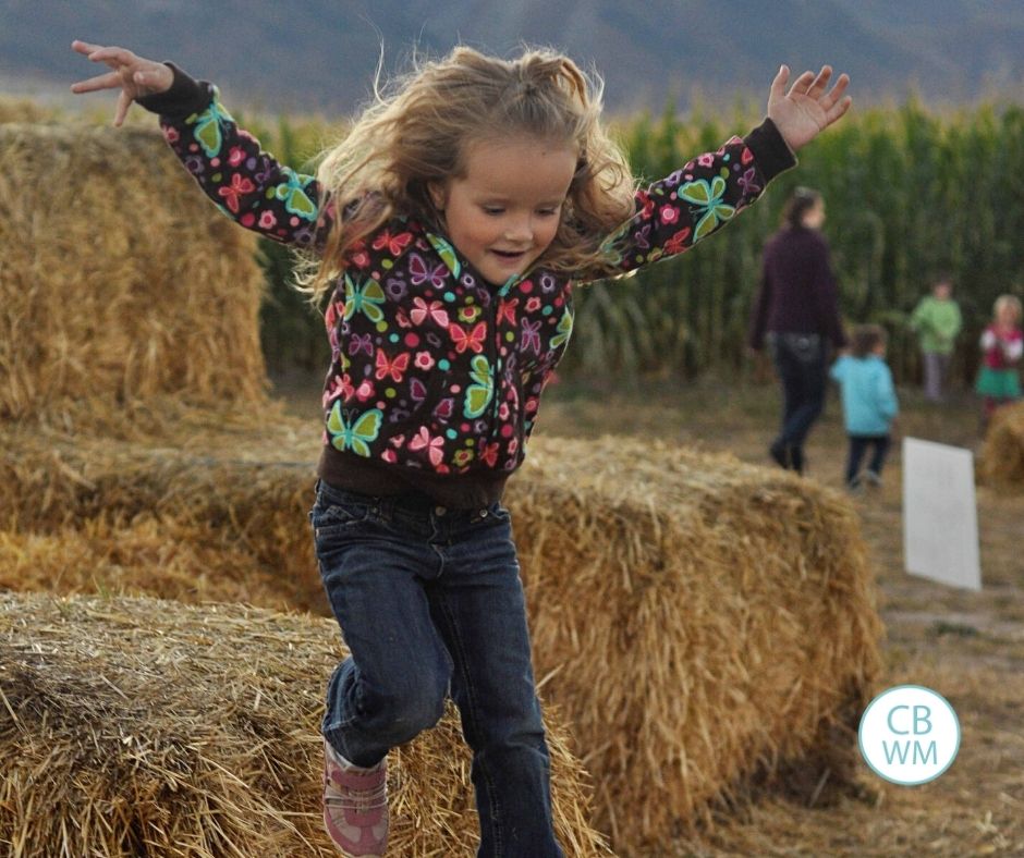 4.5 year old Kaitlyn jumping of a pile of straw bales