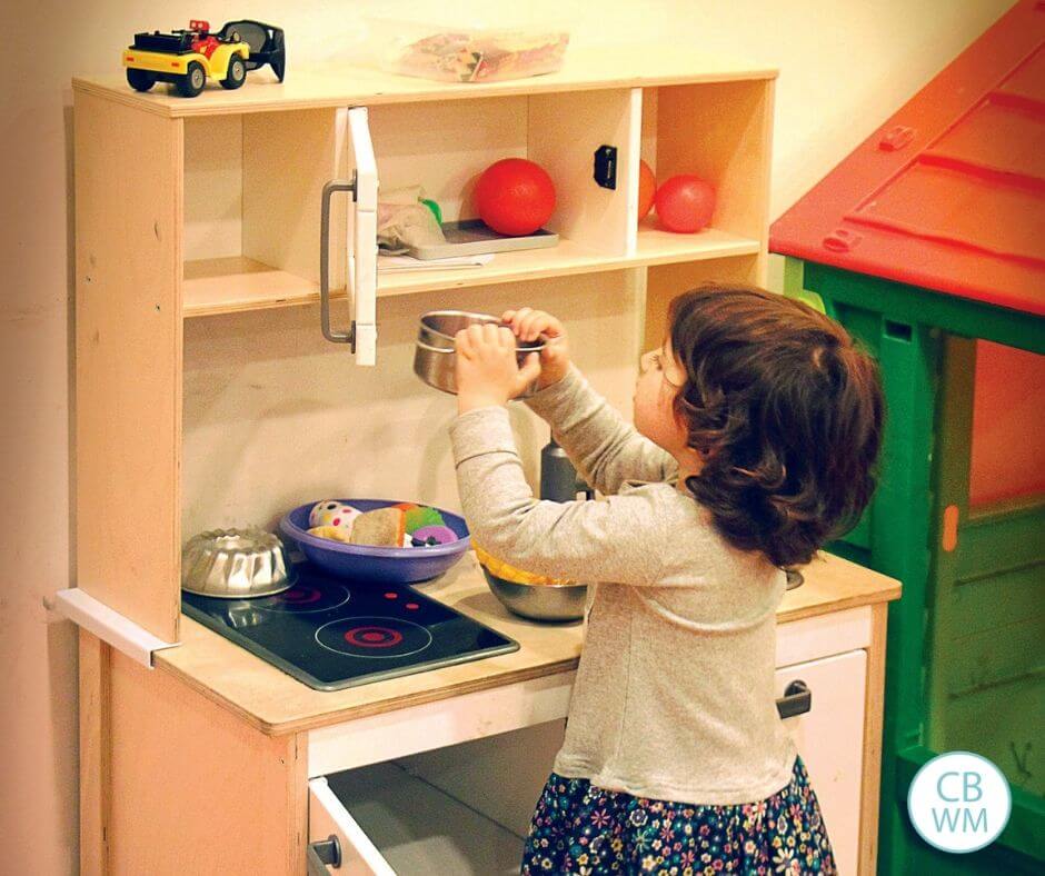 Girl playing with a toy kitchen