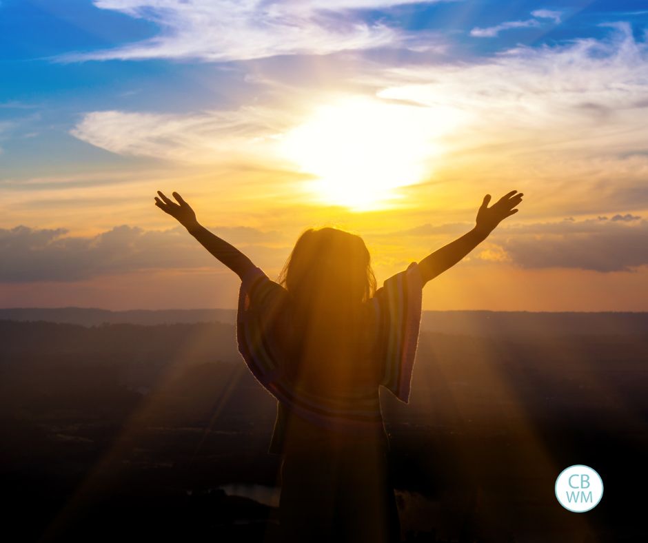 woman with arms in the air looking into the sun