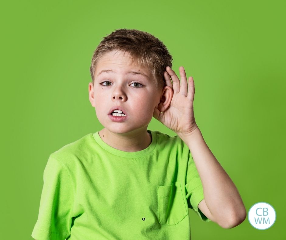 Boy holding had up to ear wearing green
