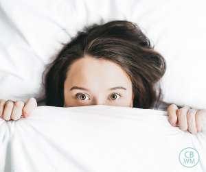 Woman in bed with white sheet covering half of her face