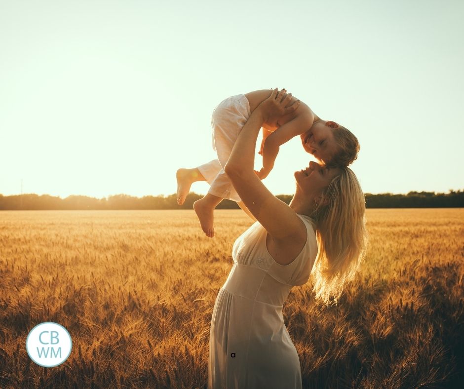 Mom holding son in the air with wheat field behind her