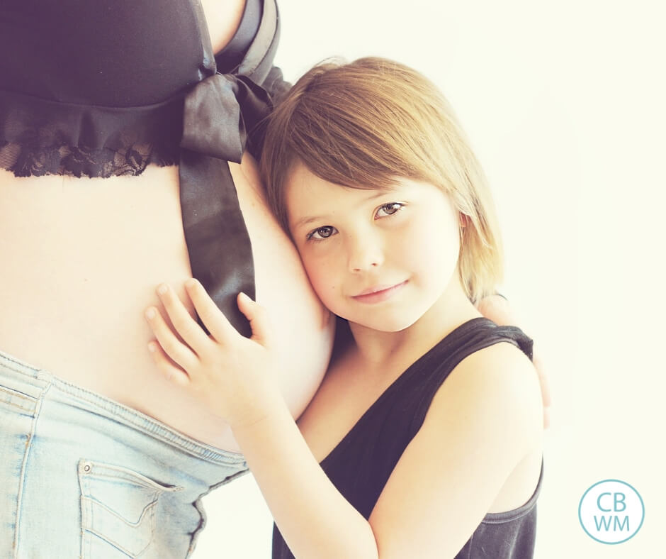 Girl hugging pregnant moms belly