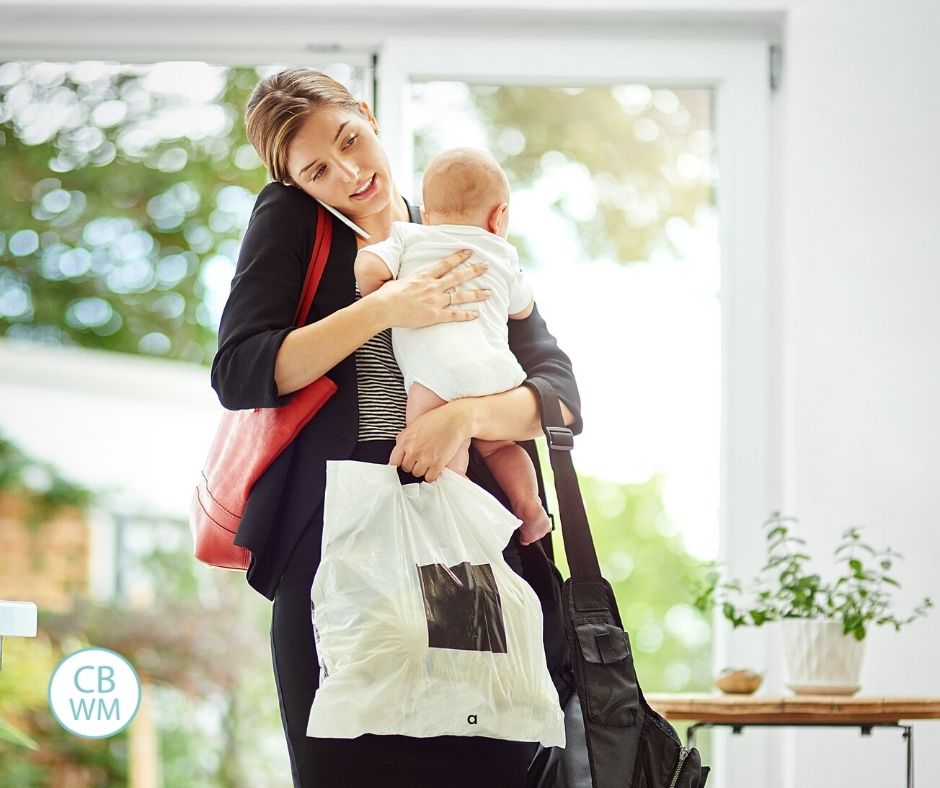 Working mom holding baby with arms full of work bags