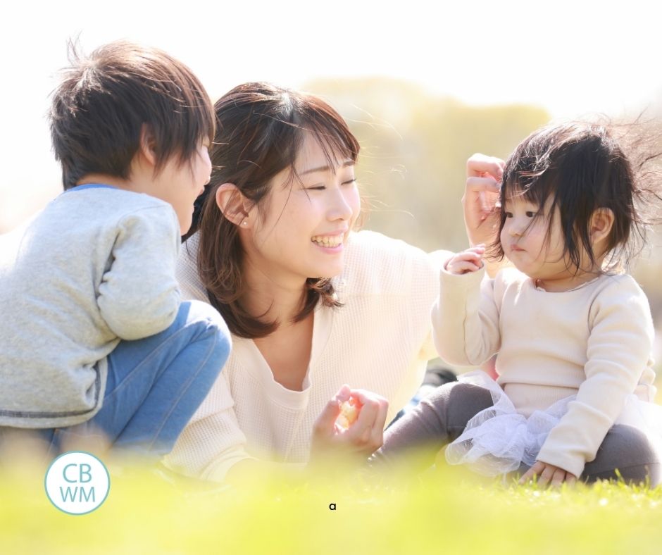 mom with her two children sitting outside in the grass