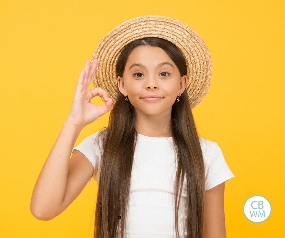 child giving okay sign in front of yellow wall