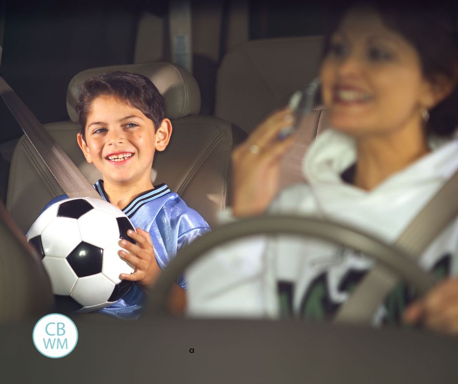 Mom driving her son who is holding a soccer ball