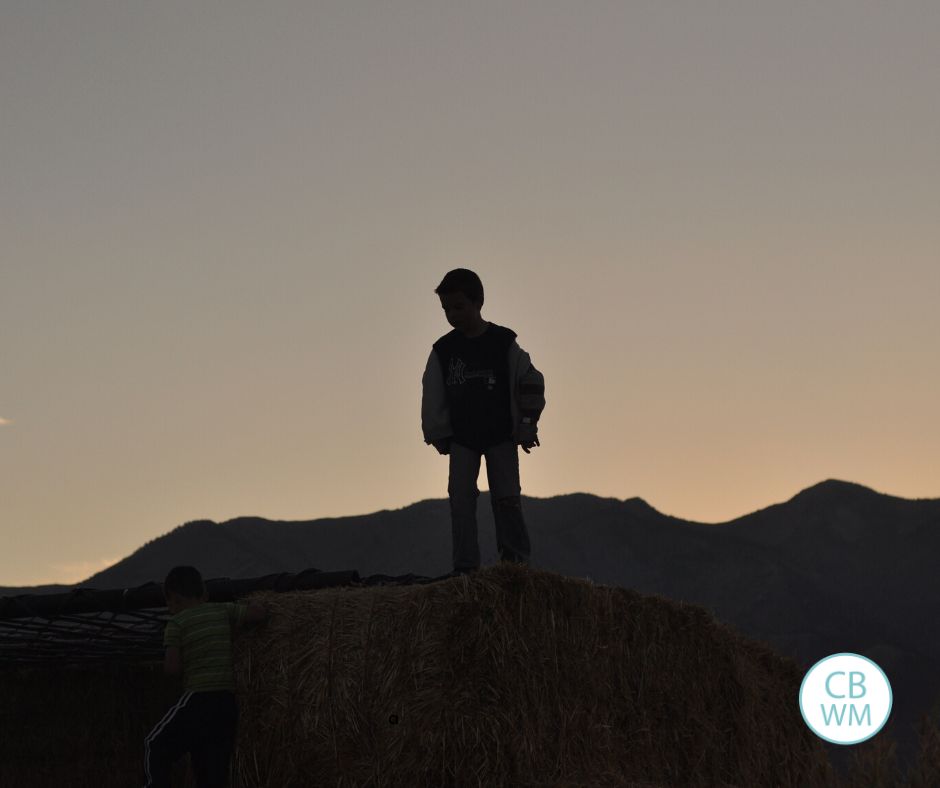 7.5 year old Brayden standing on top of a straw bale stack