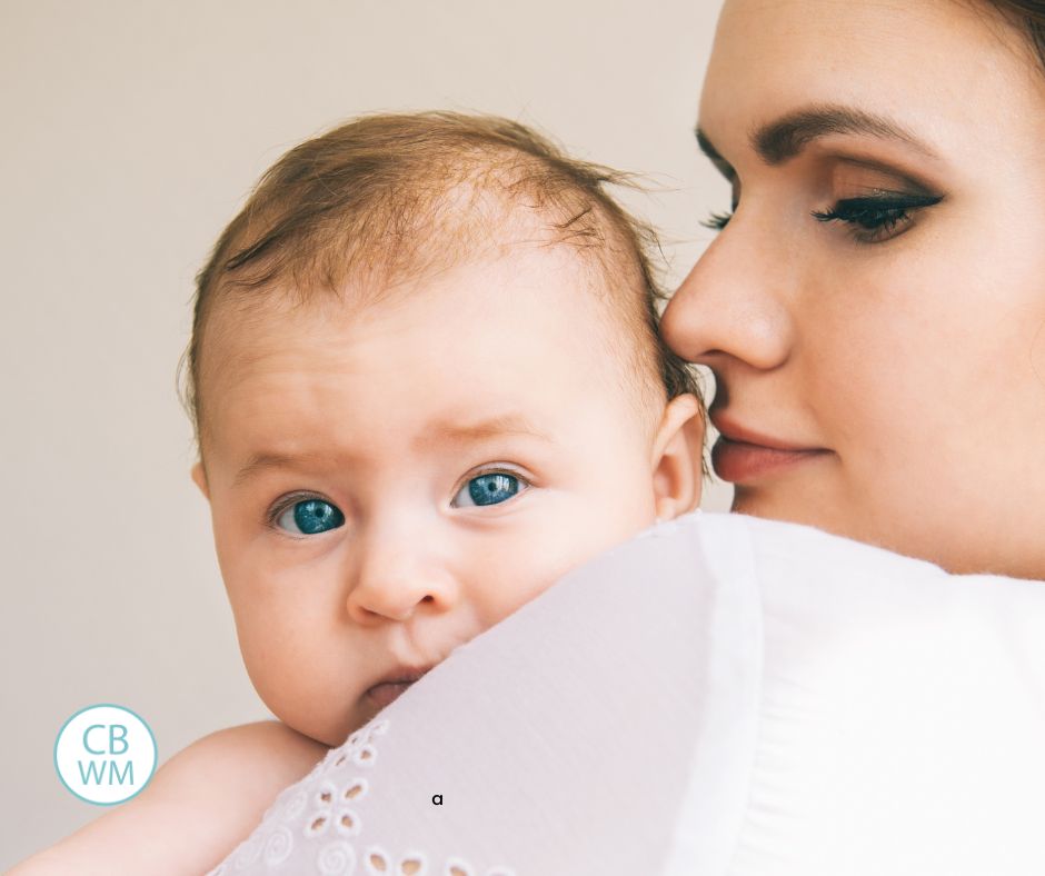 mom holding baby looking over her shoulder