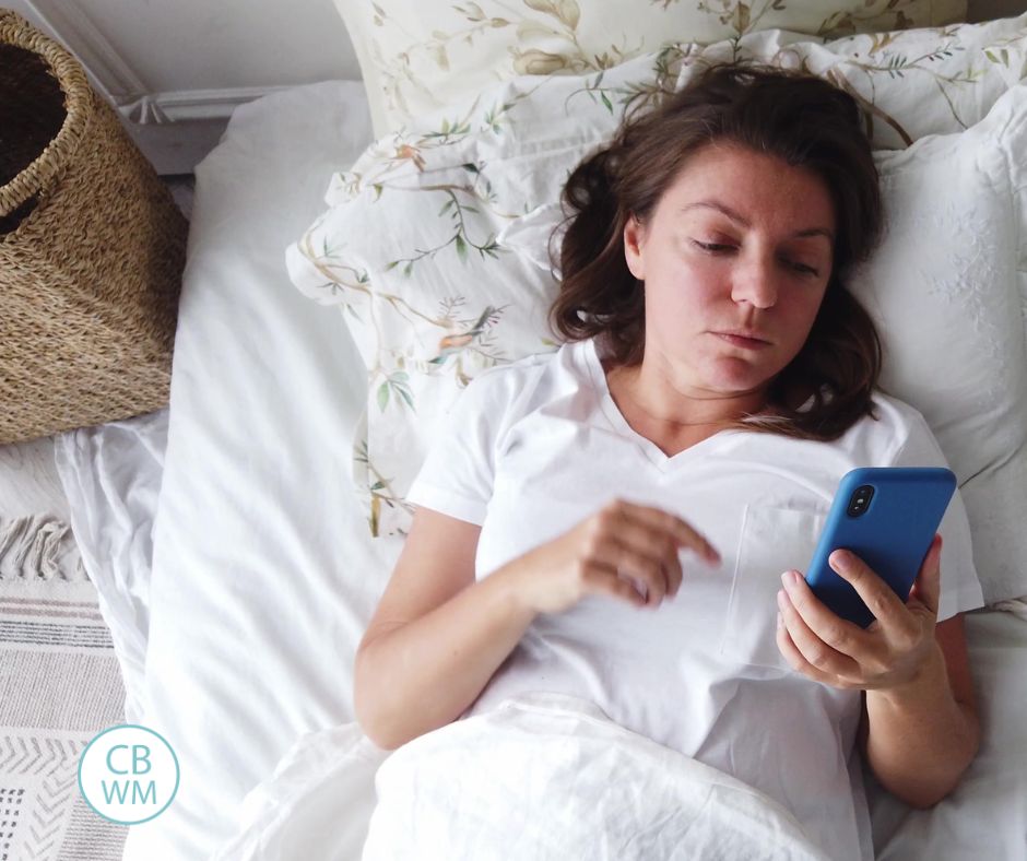 Woman in bed, sad and looking at her phone