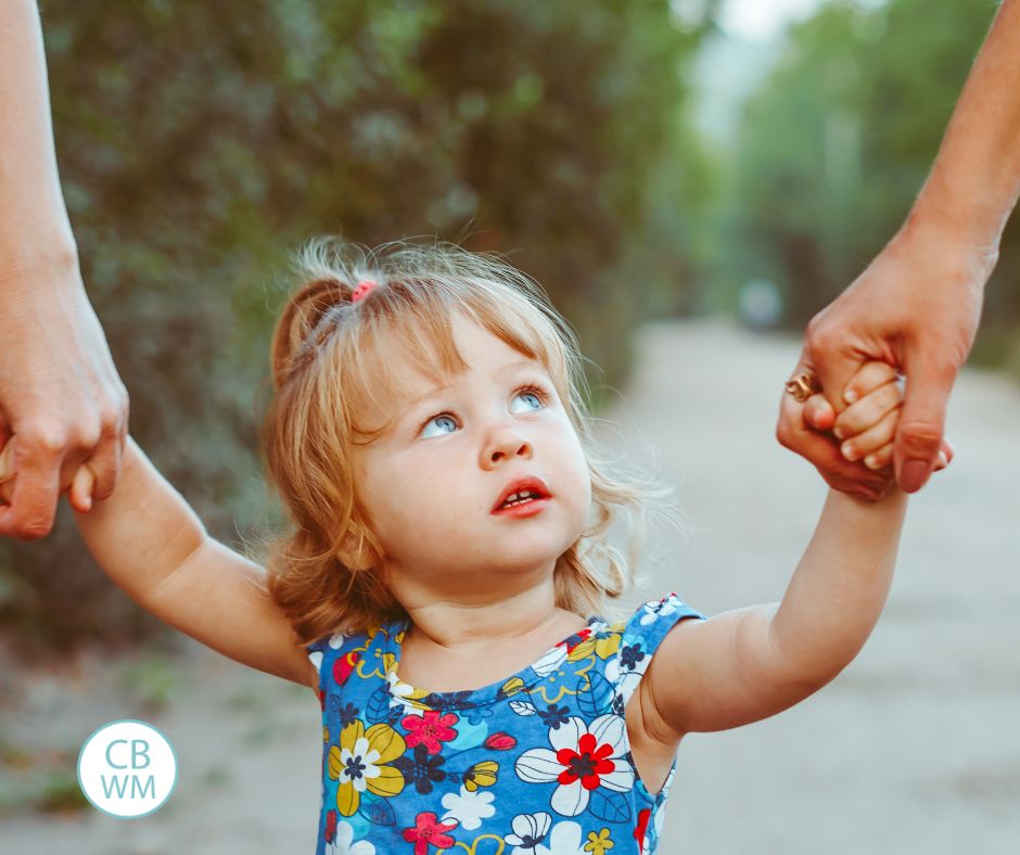 child holding hands of her parents