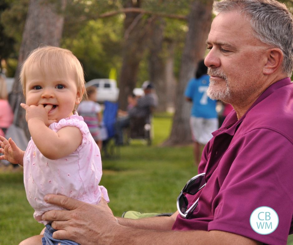 Brinley sitting on her Papa's lap at a t-ball game