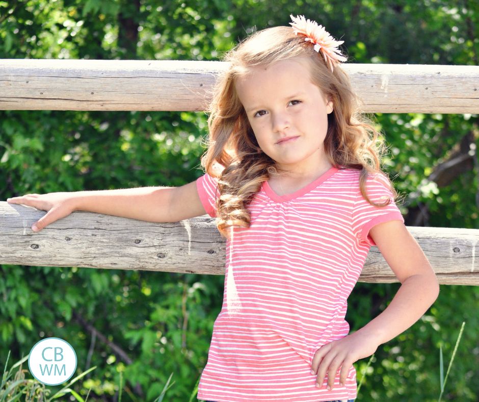 6.25 year old Kaitlyn standing by a wood fence