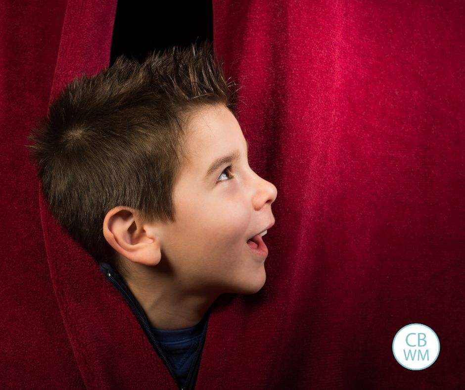 child peeking through the stage curtains