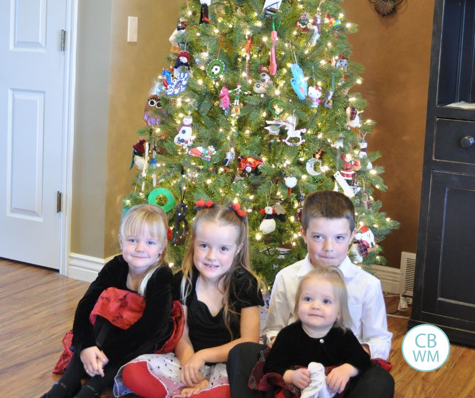 4 kids sitting in front of the Christmas tree