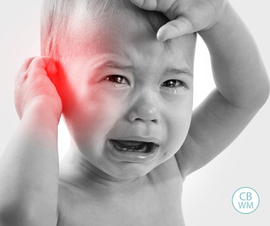 Child crying holding sore ear from ear infection