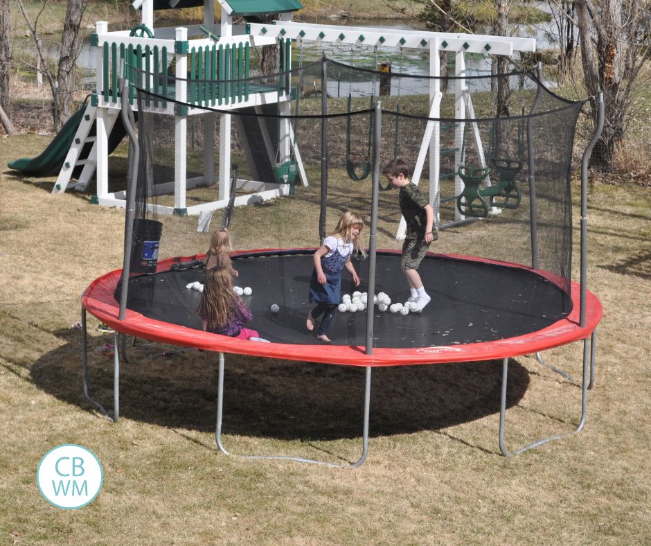 Brinley playing on the trampoline with siblings