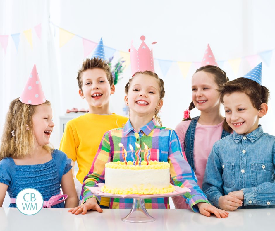 Kids surrounding a girl with a birthday cake