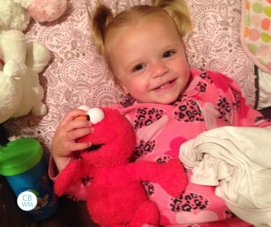 22 month old Brinley laying in bed with her Elmo stuffed animal