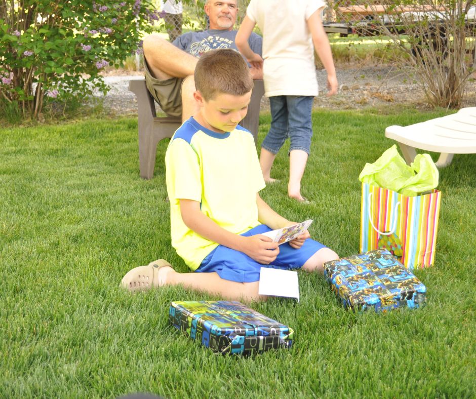 9 year old boy opening gifts outside on the grass