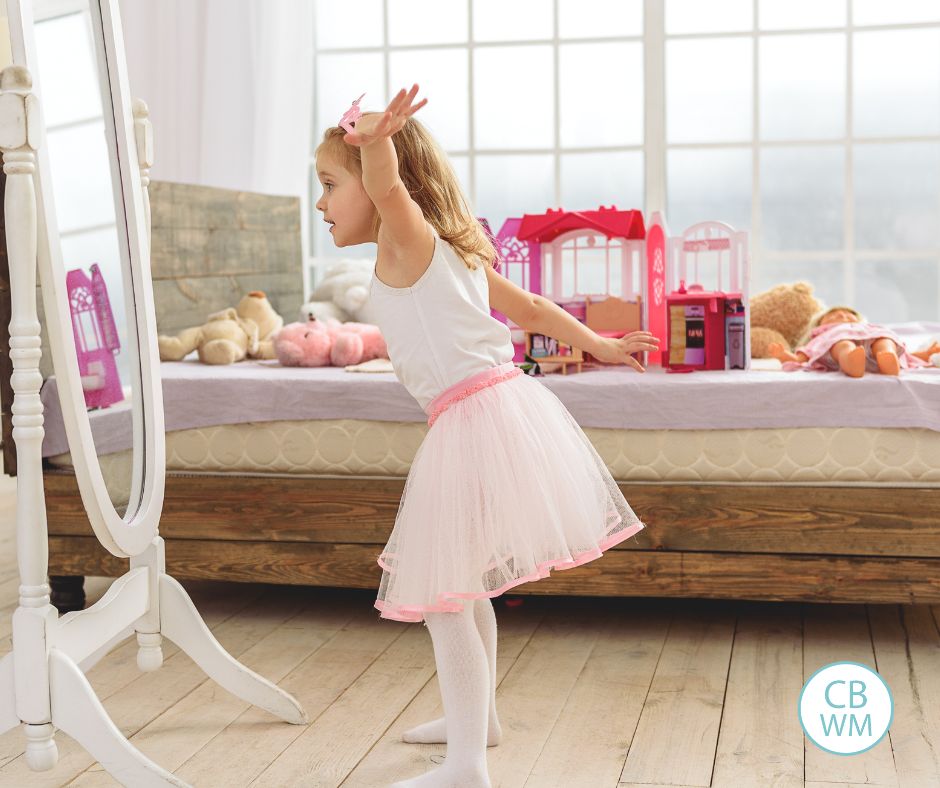 Little girl playing in her room in front of the mirror