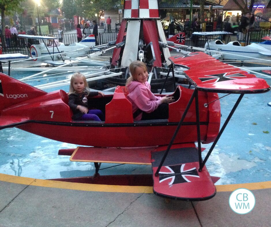 Brinley and Kaitlyn sitting in a plane on a ride at an amusement park