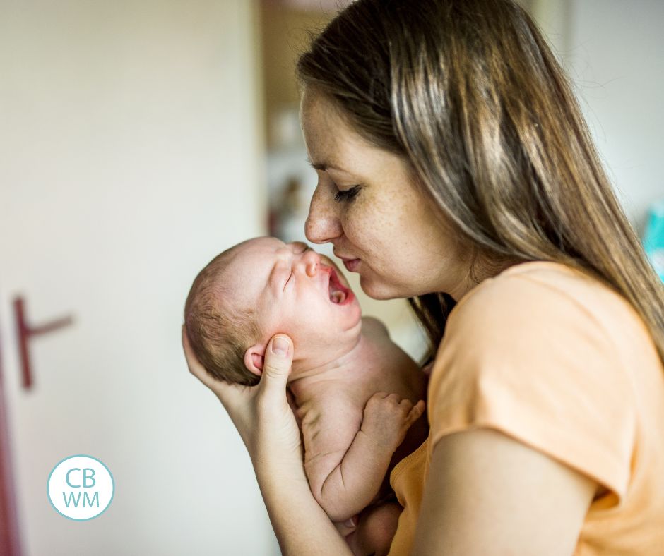 Mom kissing newborn face. Newborn is crying