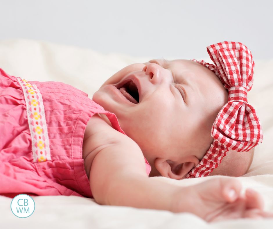 Fussy baby crying in a pink dress