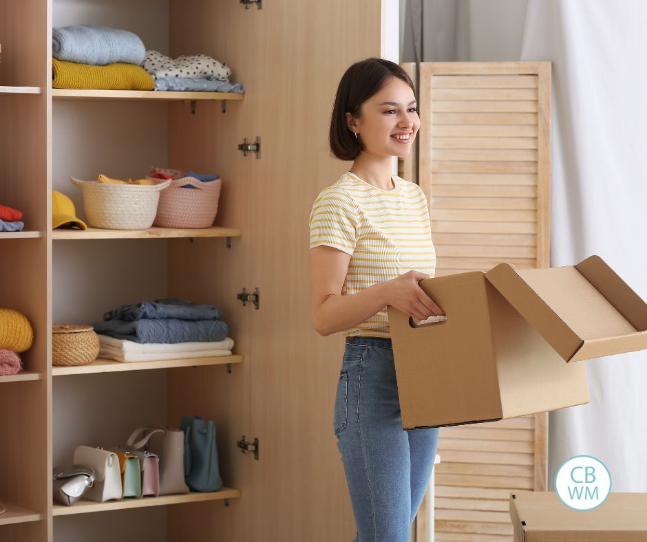 Woman holding a box as she orgnizes a closet
